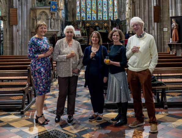 Chair Jane Povey, with trustees Chris Stephens, Caroline Nowotarski, Jane Elliott and Roger Terry standing, glass in hand, in the beautiful surroundings of St Mary's Church