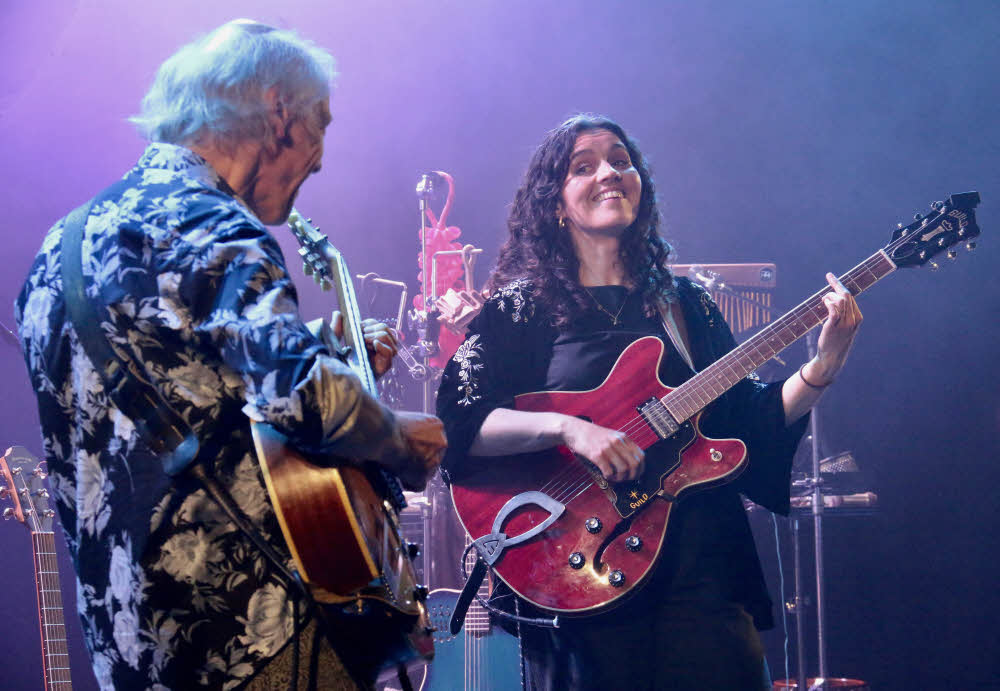 Pete Oxley looking at Hattie Whitehead who is grinning back as both play their guitars