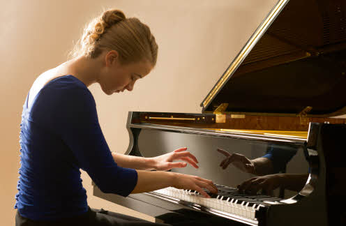 Elisabeth viewed in profile, seated at and playing the piano. Photo by Peter Barritt